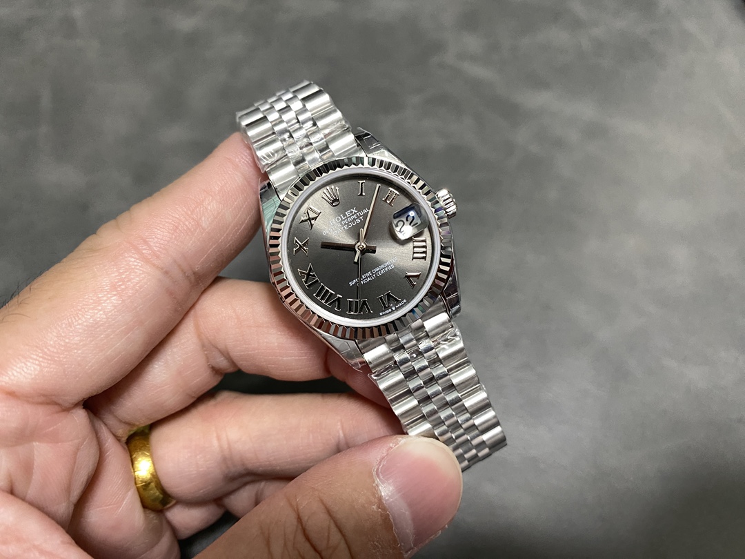 Close-up shot of a super clone Rolex Datejust with grey dial and Roman numerals, held in hand to show the fluted bezel and Jubilee bracelet