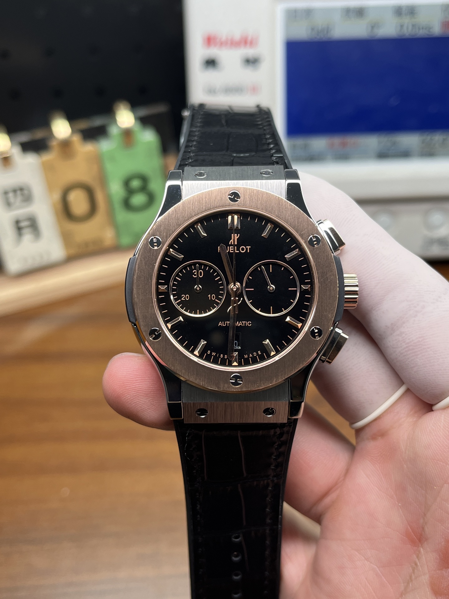 Front view of Hublot replica chronograph with rose gold bezel black dial and black strap