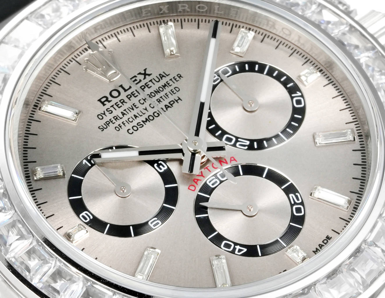 Rolex Daytona dial close-up showing sunburst silver finish, black rings and applied markers