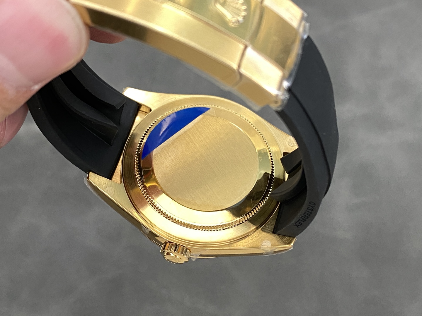 Back of gold replica watch showing brushed caseback with protective sticker and engravings