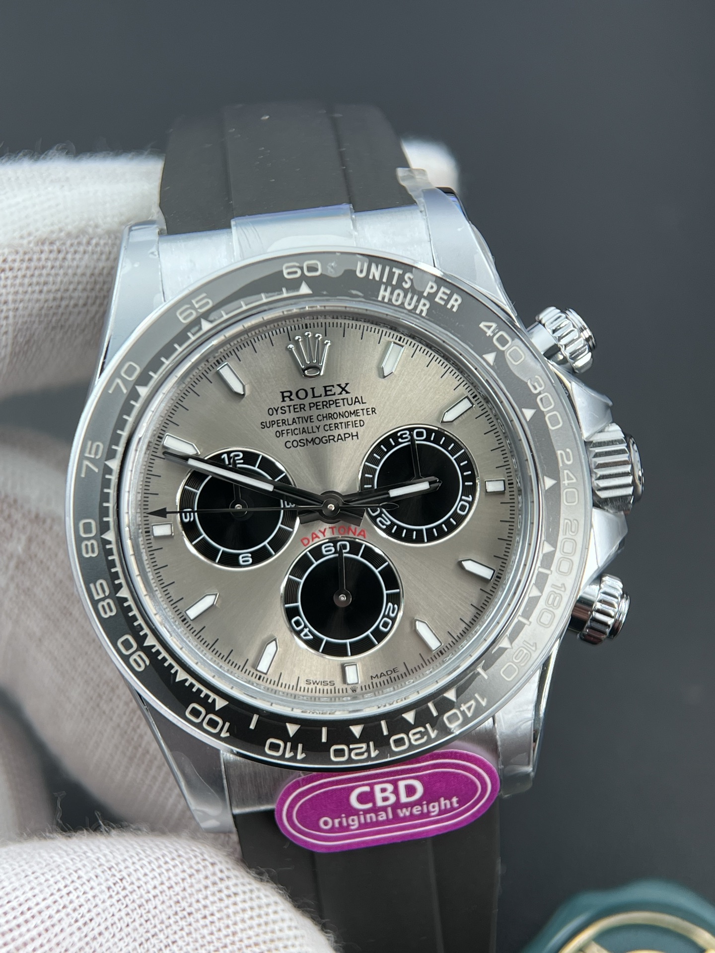 Silver dial Rolex Daytona replica with black subdials and rubber strap, featuring CBD original weight sticker, highlighting the 4131 clone movement model.