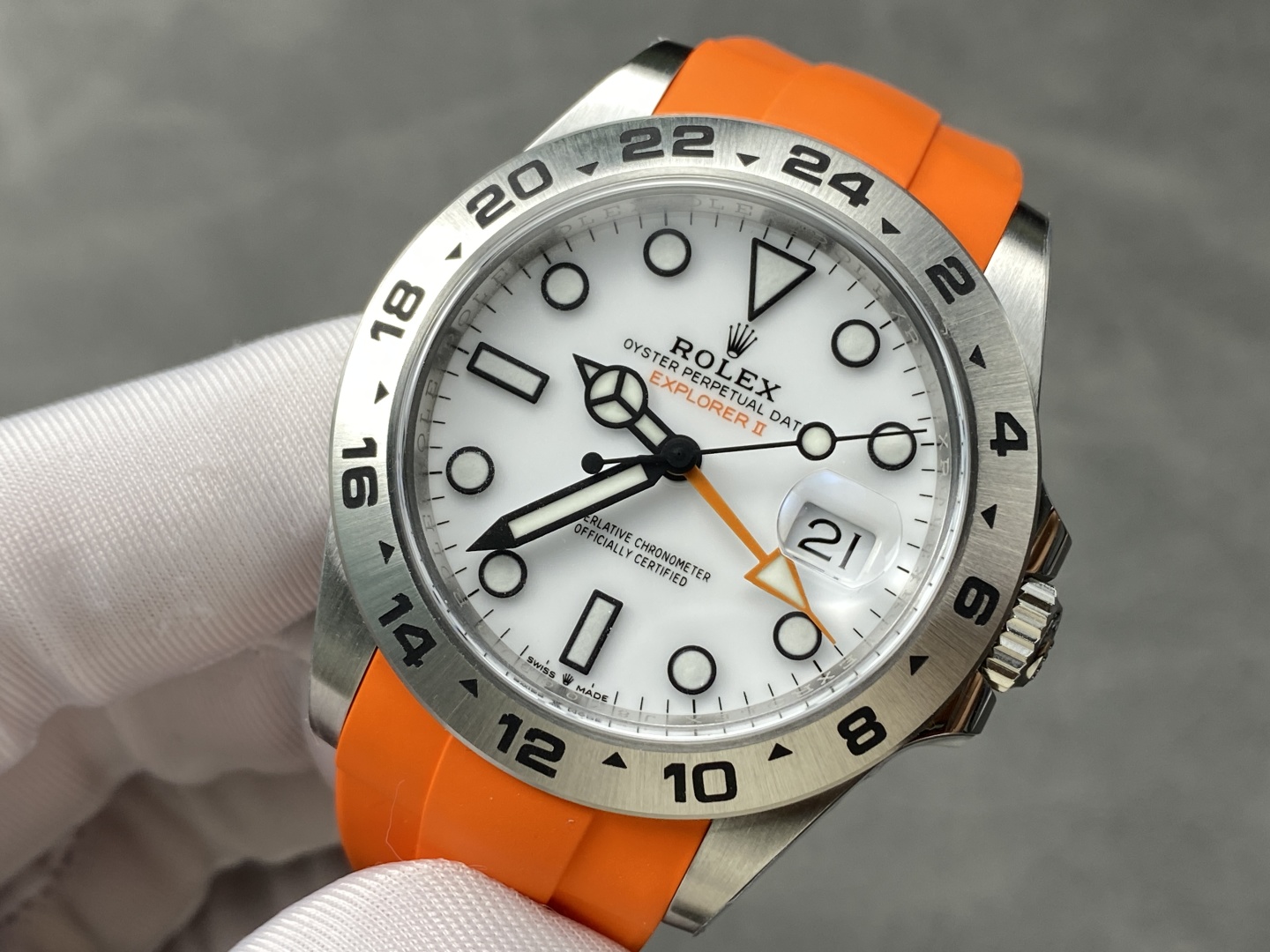 High-quality close-up photo of Rolex Explorer II replica dial showing white face, orange GMT hand, date window and 24-hour bezel