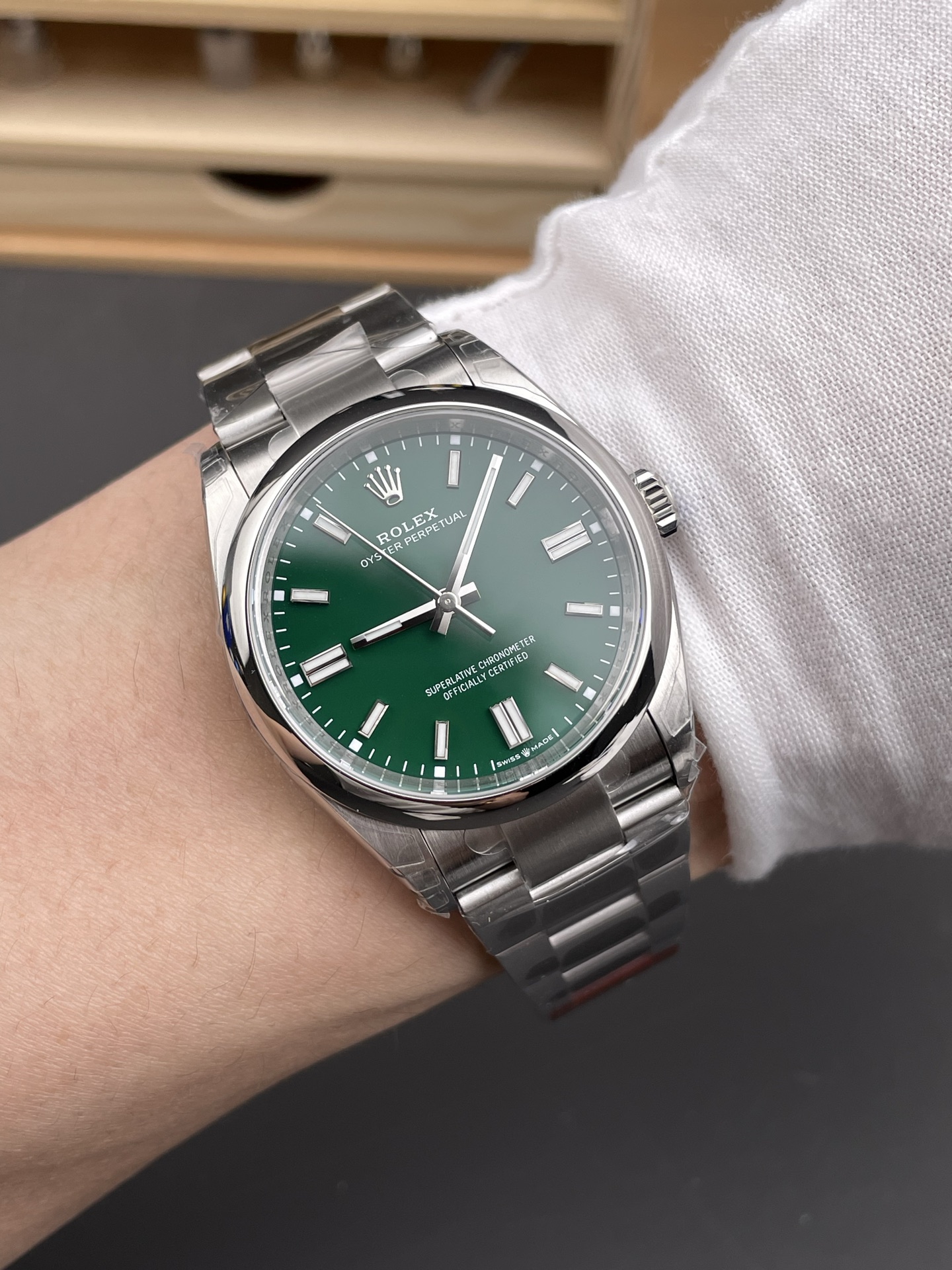 Gruene Oyster Perpetual am Handgelenk mit poliertem Gehaeuse, Oyster-Band und weissem Hemdaermel