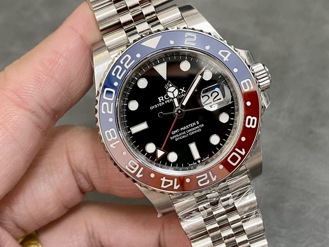 Close-up of a high quality replica Rolex GMT-Master II Pepsi with blue and red ceramic bezel, black dial, red GMT hand, and jubilee bracelet, held in hand.