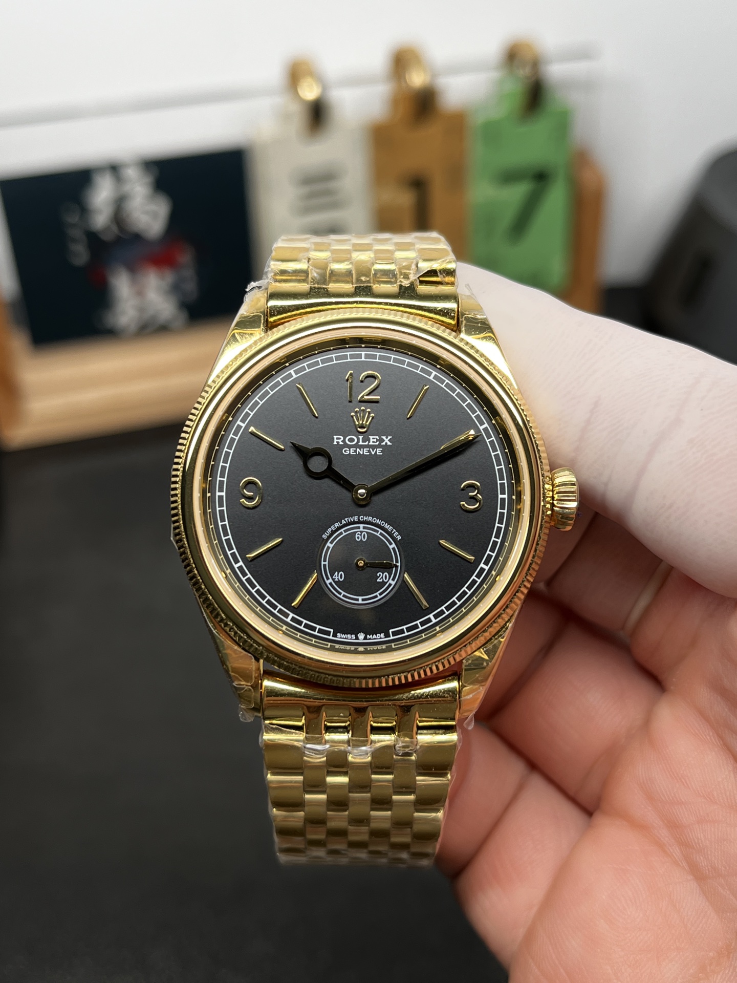 Gold rolex replica watch with black dial and small seconds sub-dial on wrist