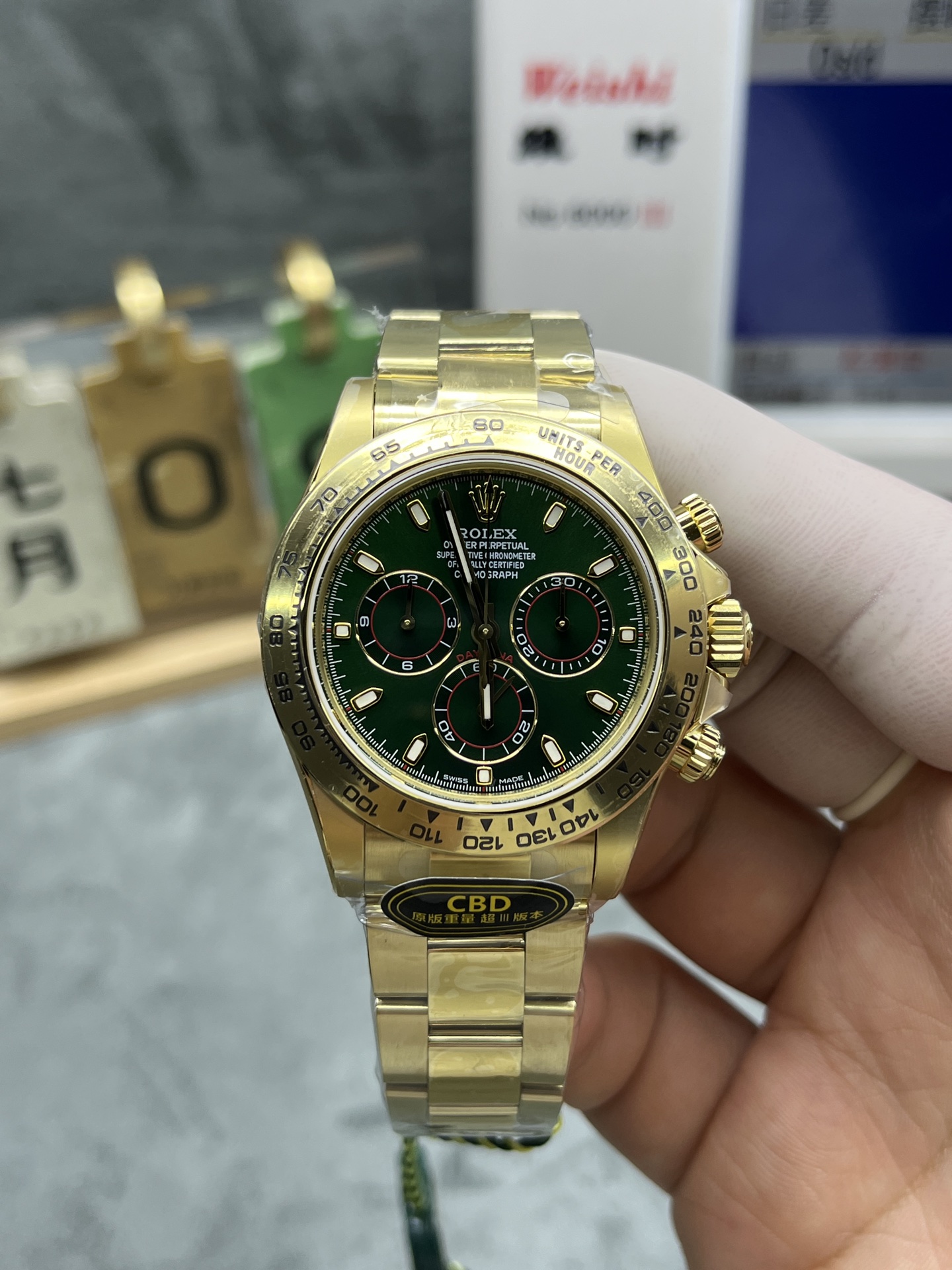 Front face of a green dial gold Daytona replica with CBD sticker