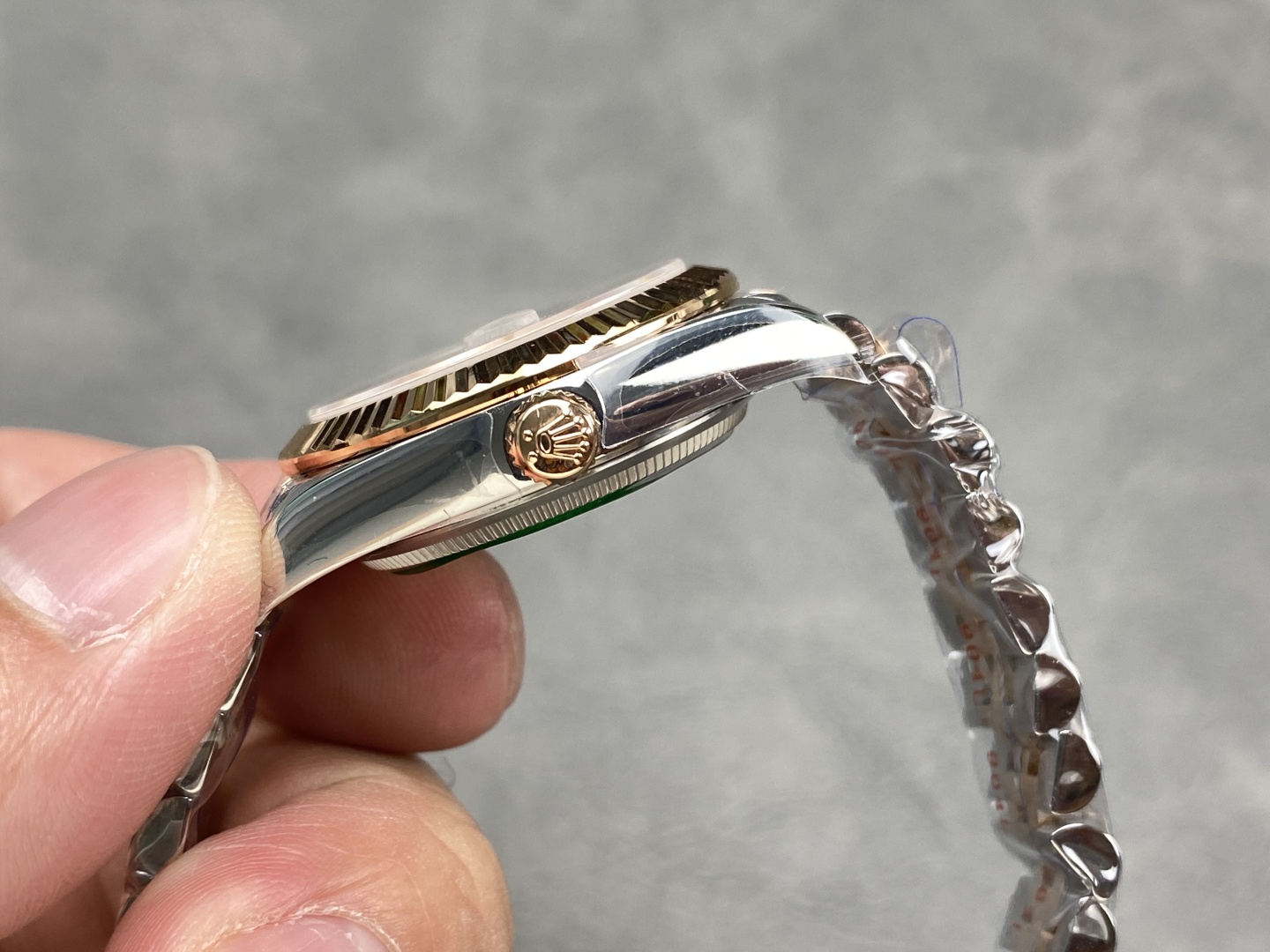 Detalle lateral de la caja y la corona de un Rolex falso de dos tonos con acabado pulido.