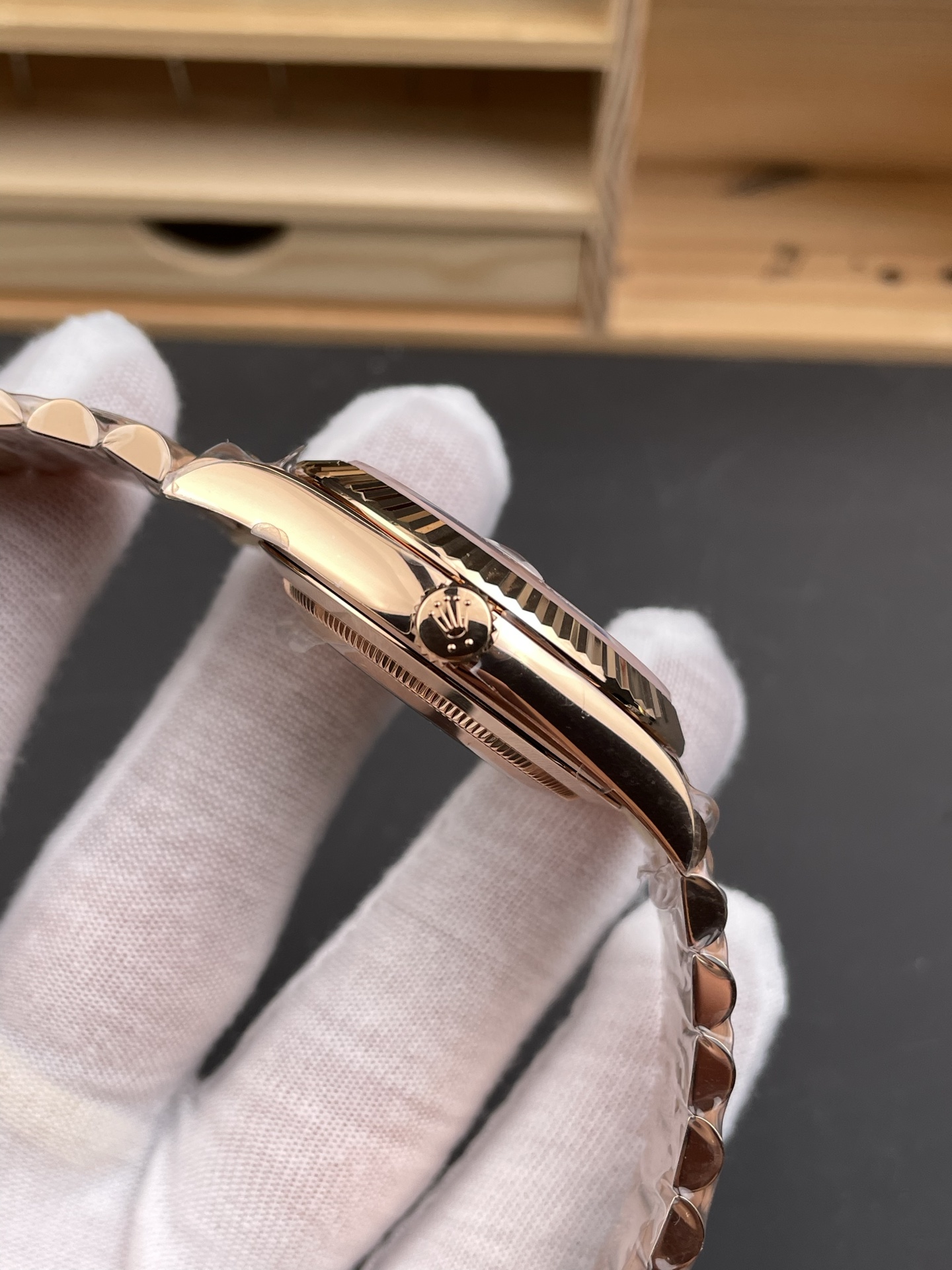 Rose gold replica watch side view with crown fluted bezel and protective wrapping