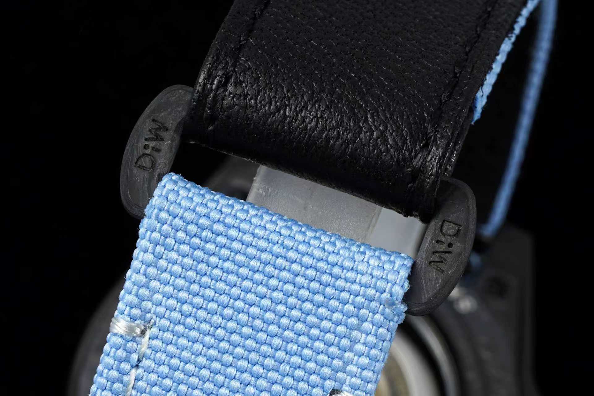 Macro shot of light blue woven strap and black leather upper with DiW engraved hardware