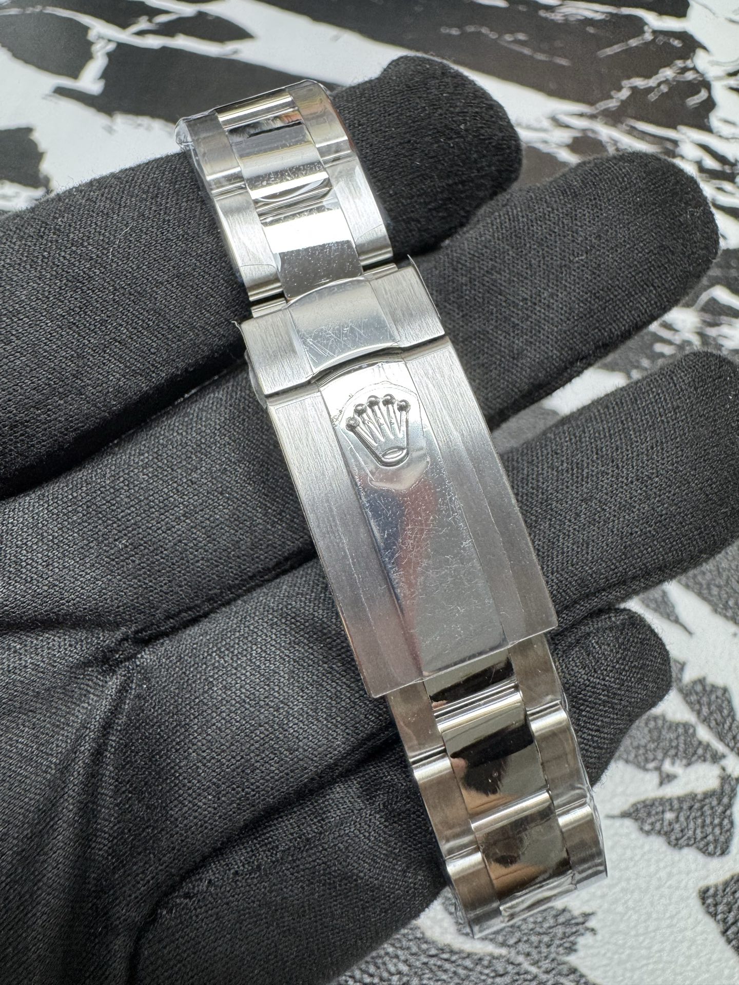 Oyster bracelet clasp with embossed Rolex crown logo, brushed steel finish.