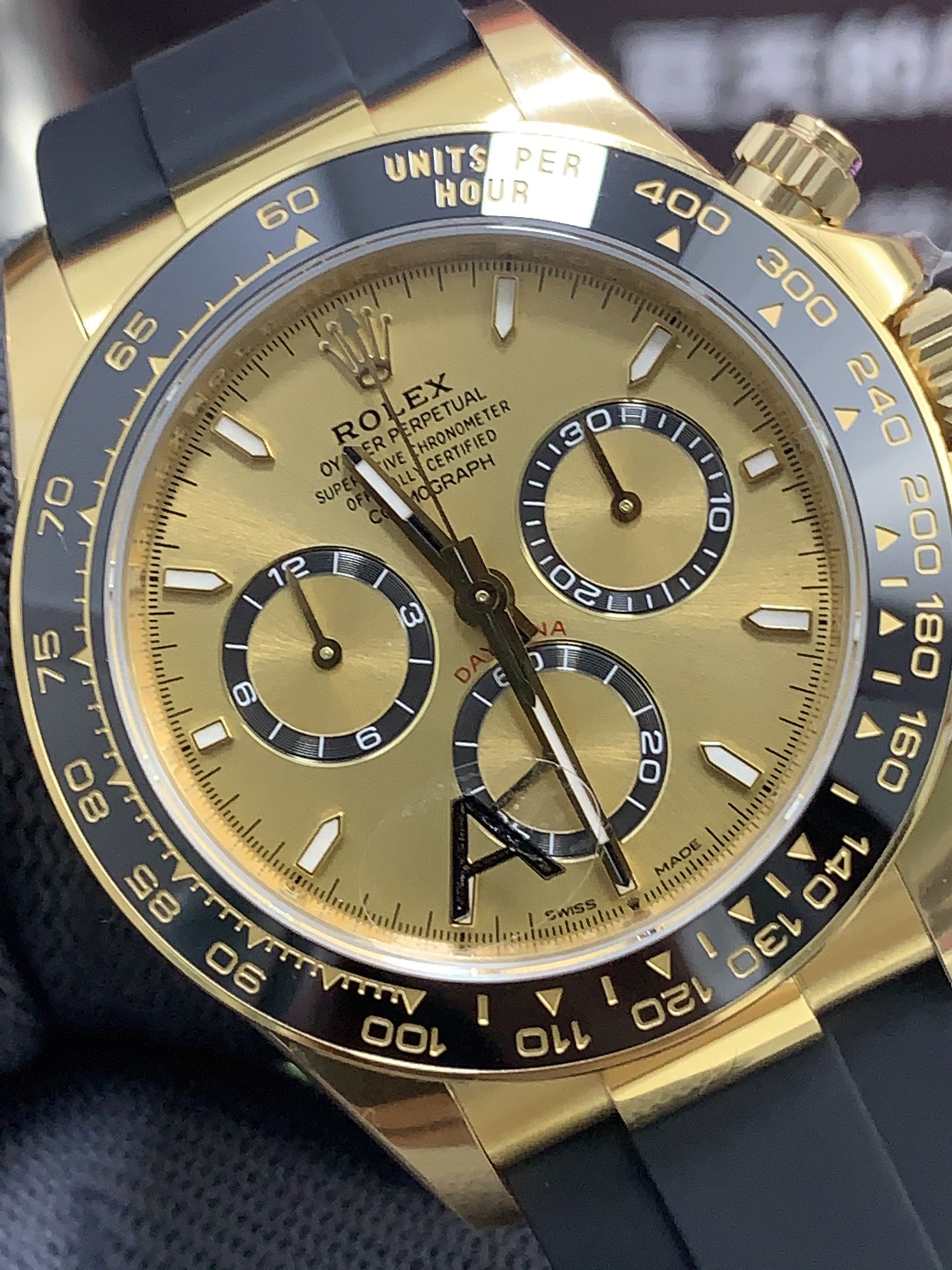 Close-up dial view of gold-tone rolex copy watch with black ceramic tachymeter bezel
