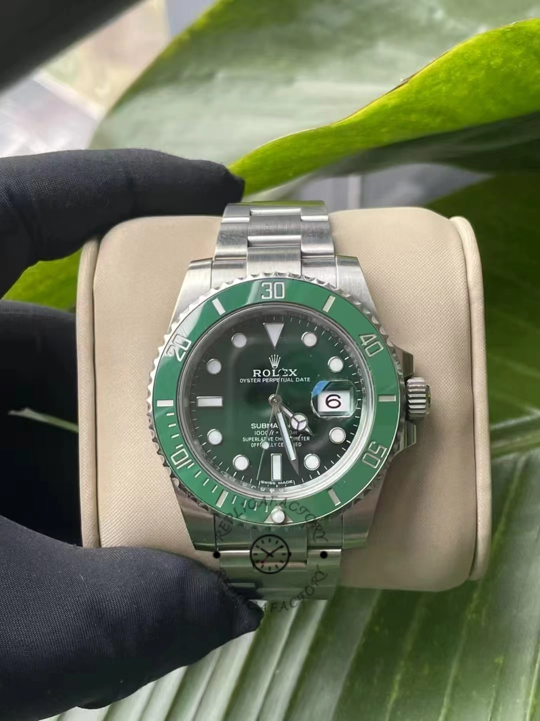 Front view of the Rolex Submariner Date 116610LV with green dial and bezel, on a beige cushion.